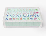 A clear acrylic display box with a removable lid. The acrylic box stores The Mahjong Line mahjong tile set.