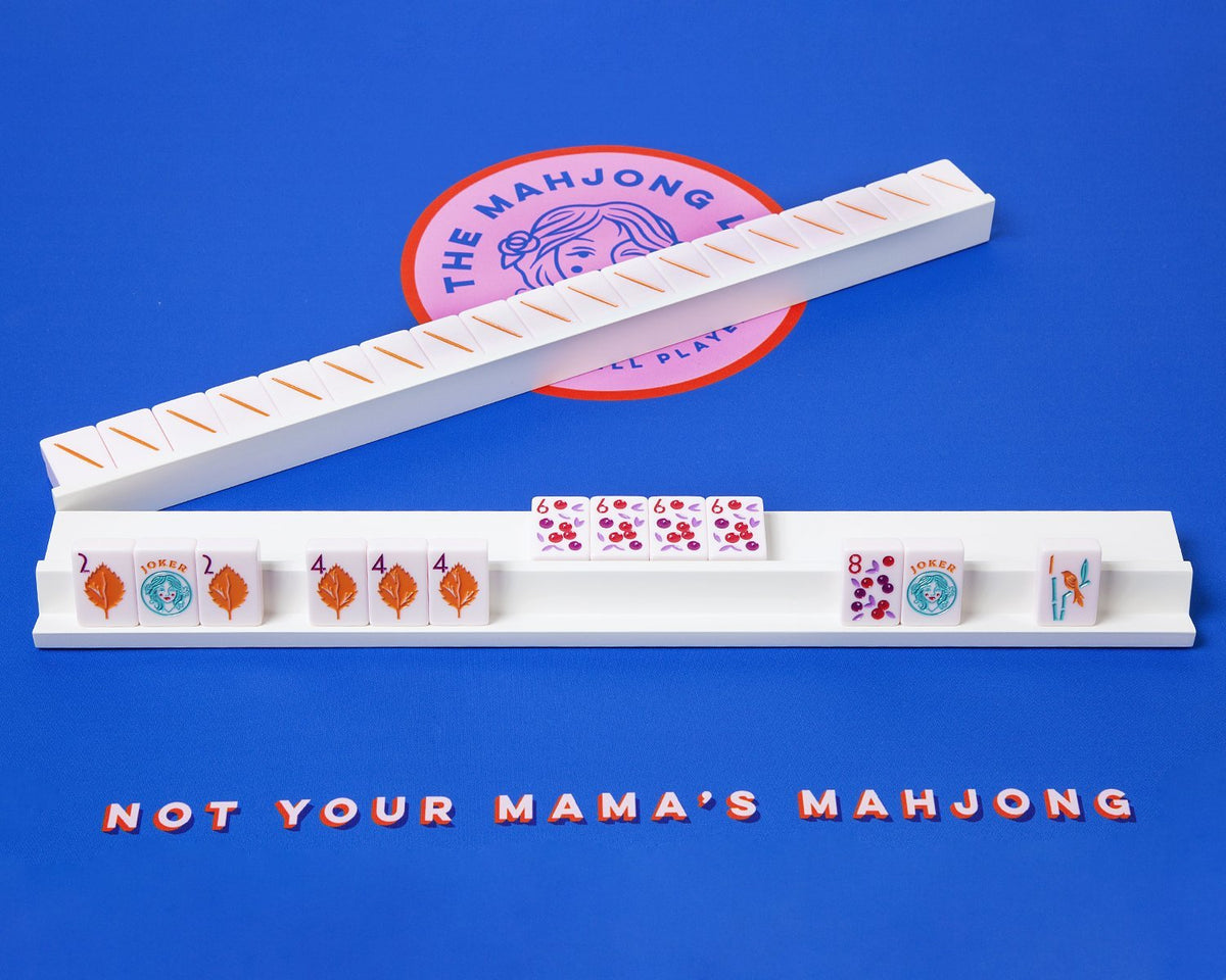 White painted wooden Mahjong rack and pushers placed on top of a Mahjong mat. The racks and pushers are custom made for our mahjong sets for sale.