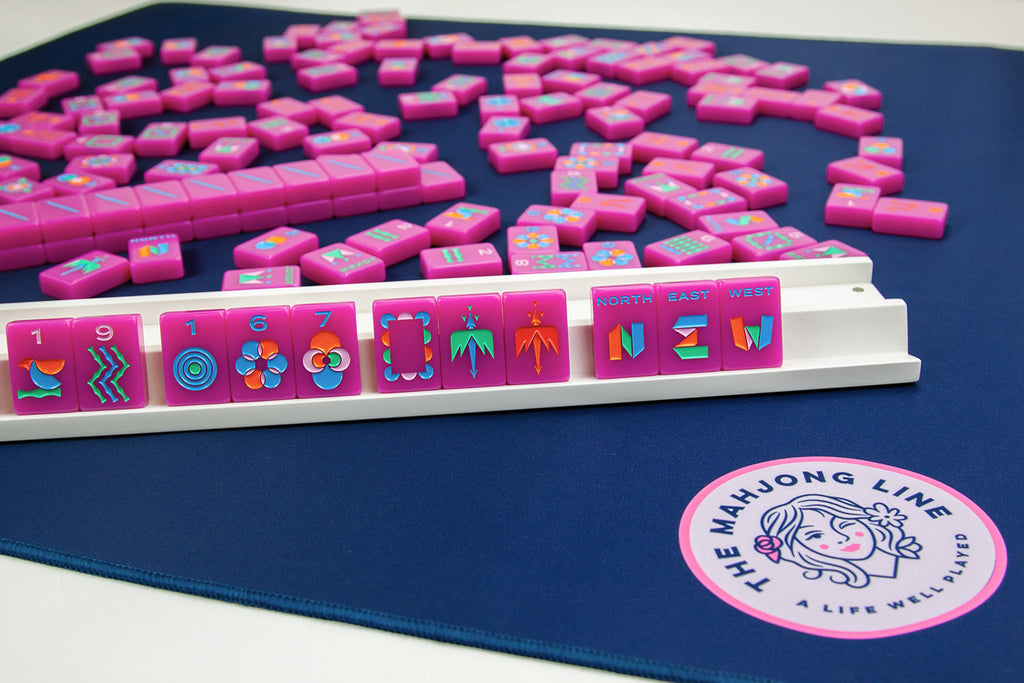 The Neon Purple 2.0 American mahjong color way tiles displayed on the white racks on top of the navy playing mat by The Mahjong Line. 